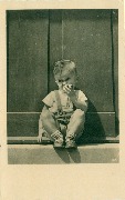 Garçonnet assis au pas d'une porte croquant une pomme