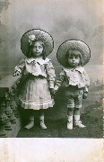 Deux enfants à grands chapeaux devant un décor 